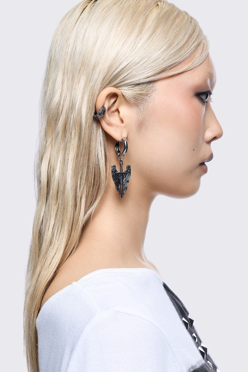 A 5-piece set of mismatched silver-toned earrings and an ear cuff featuring gothic and religious motifs, including crosses, a Virgin Mary medallion, and a winged sword dangle.
