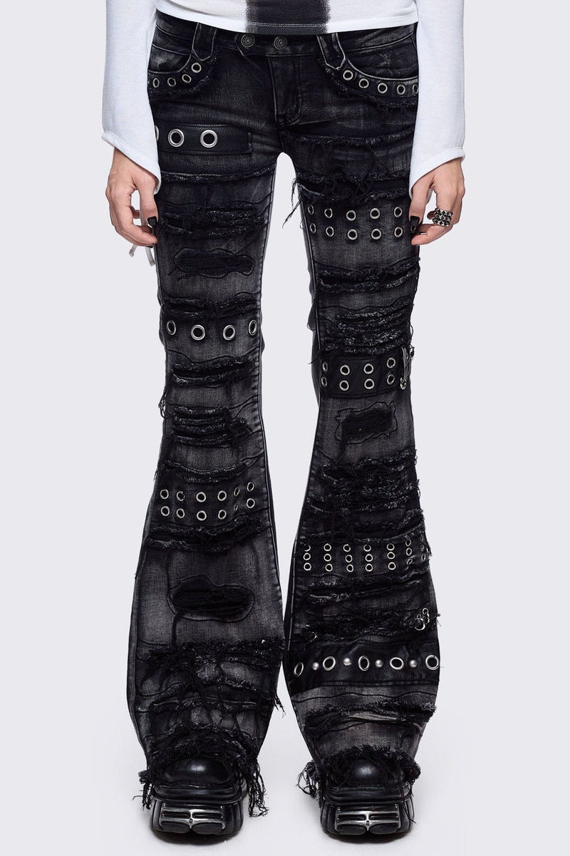 Black washed flare jeans featuring heavy distressed and shedded, eyelet, piercing and stud details.