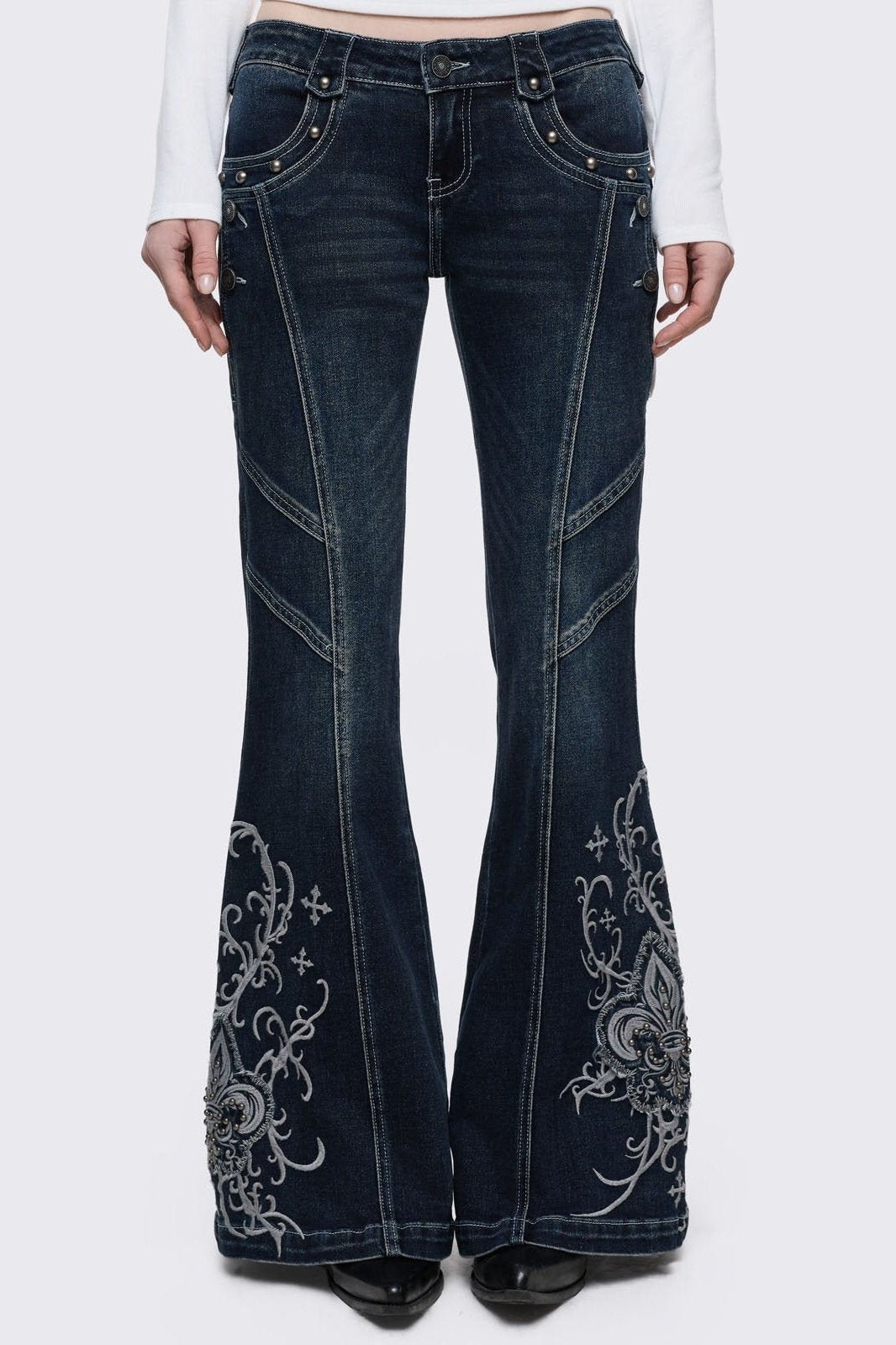 Dark blue wash flared jeans featuring gothic floral and fleur-de-lis embroidery on the lower legs and seams details.