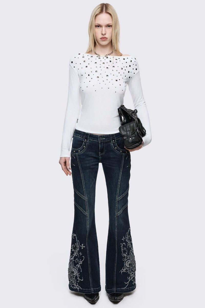 Dark blue wash flared jeans featuring gothic floral and fleur-de-lis embroidery on the lower legs and seams details.