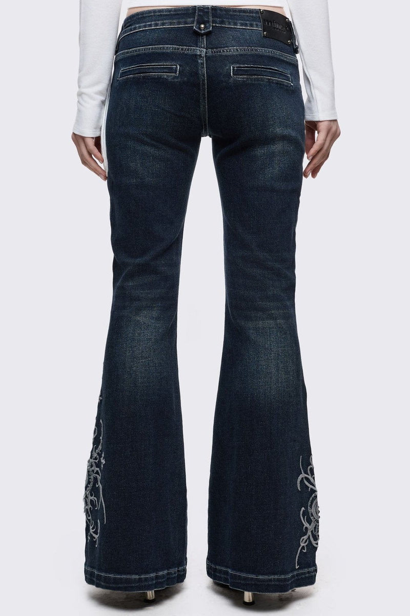 Dark blue wash flared jeans featuring gothic floral and fleur-de-lis embroidery on the lower legs and seams details.