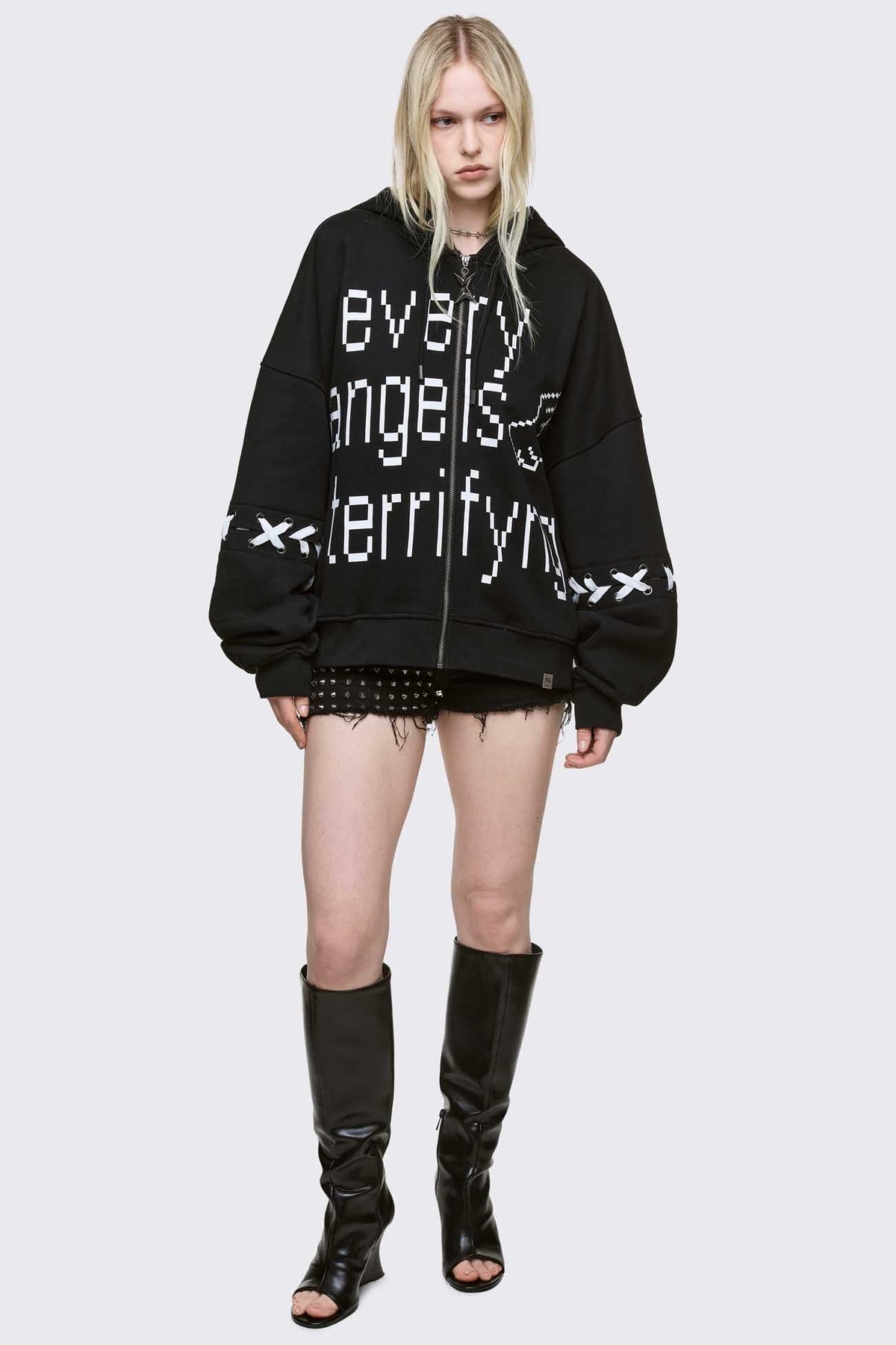 Black zip up hoodie jacket with "Every angels terrifying" graphic print and white lace-up details.