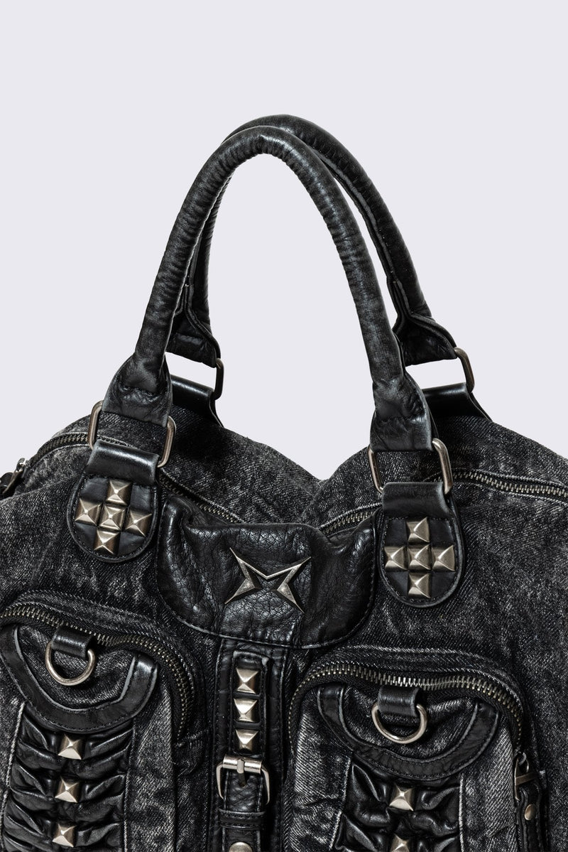 Black acid-wash denim shoulder bag with studs, ruched pockets and buckle details in a grunge Y2K style.