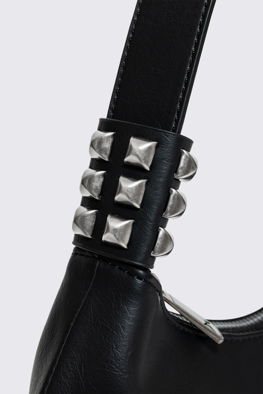 Black faux leather shoulder bag with white sinner cross print, studded panels and grunge aesthetic.