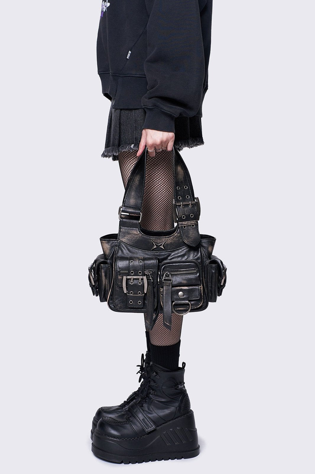 Black leather handbag with multiple pockets, buckles, and a star design, featuring an edgy, utilitarian style.