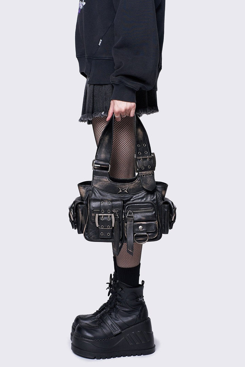Black leather handbag with multiple pockets, buckles, and a star design, featuring an edgy, utilitarian style.