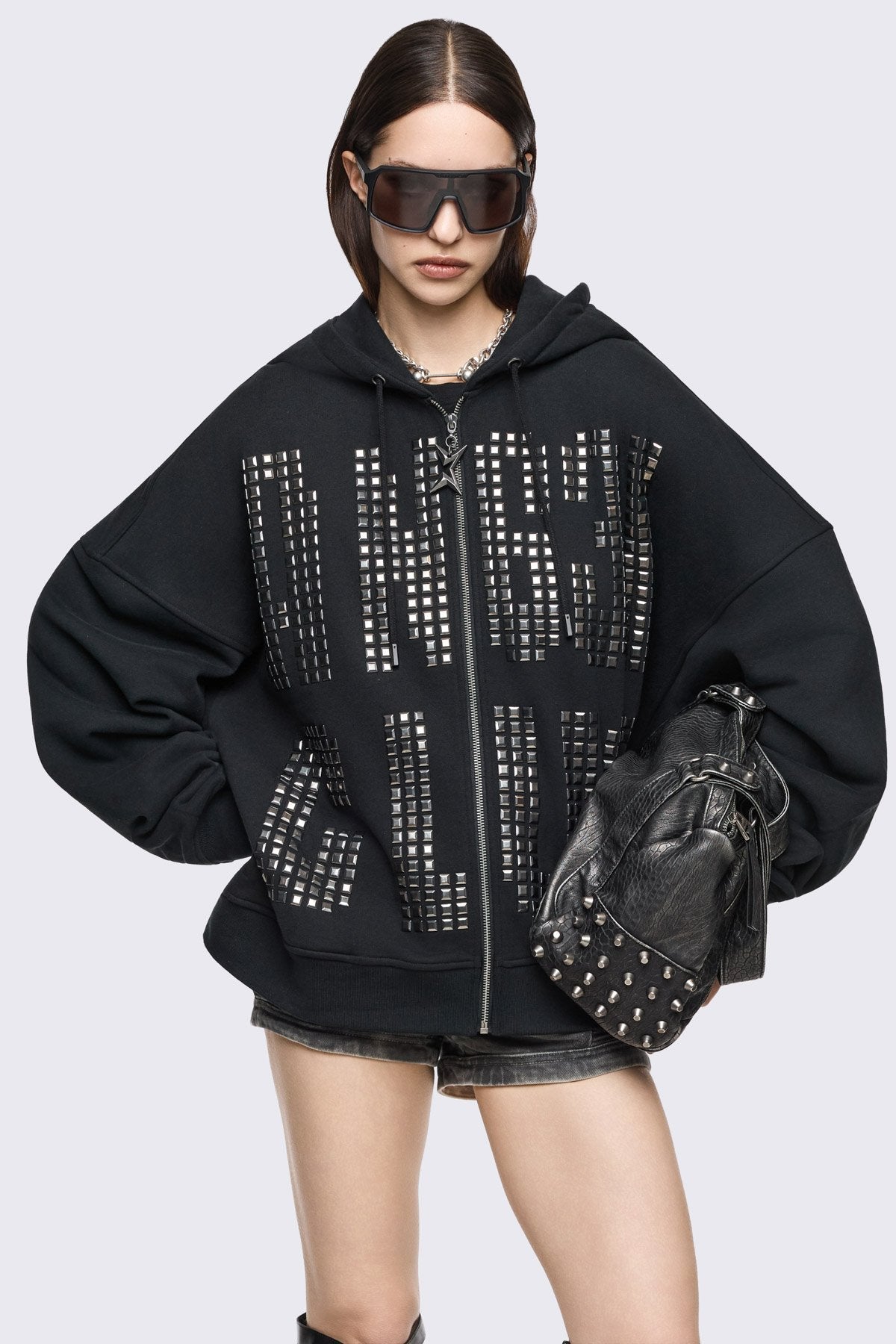 Black cotton zip-up hoodie with studded Angel Club design, oversized fit and grunge streetwear vibe.