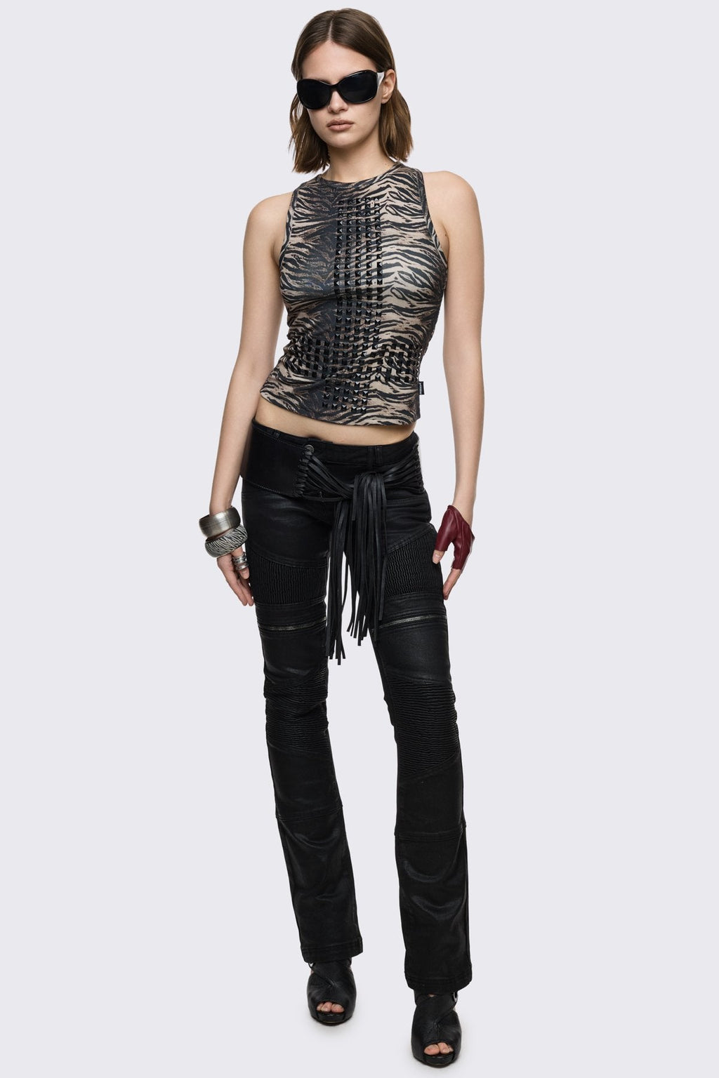 Bootcut jeans in black coated denim with ribbed paneling and zipper details, low-rise grunge aesthetic.