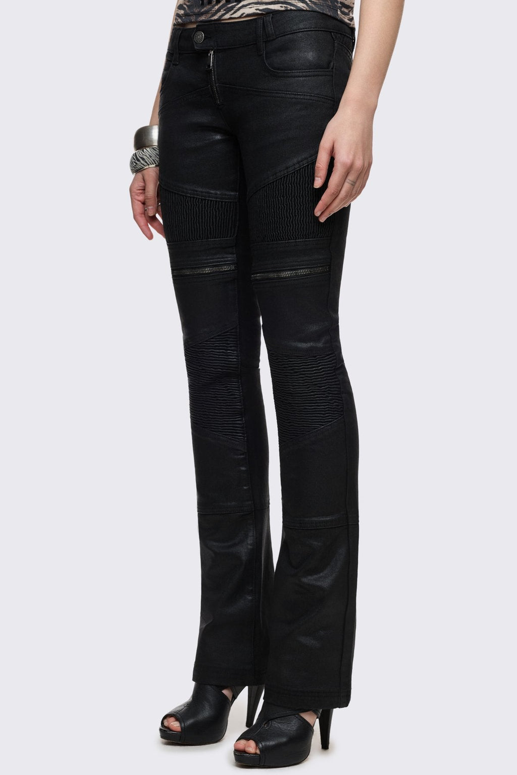 Bootcut jeans in black coated denim with ribbed paneling and zipper details, low-rise grunge aesthetic.