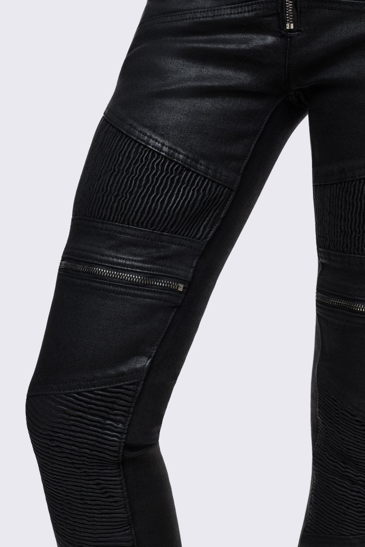 Bootcut jeans in black coated denim with ribbed paneling and zipper details, low-rise grunge aesthetic.