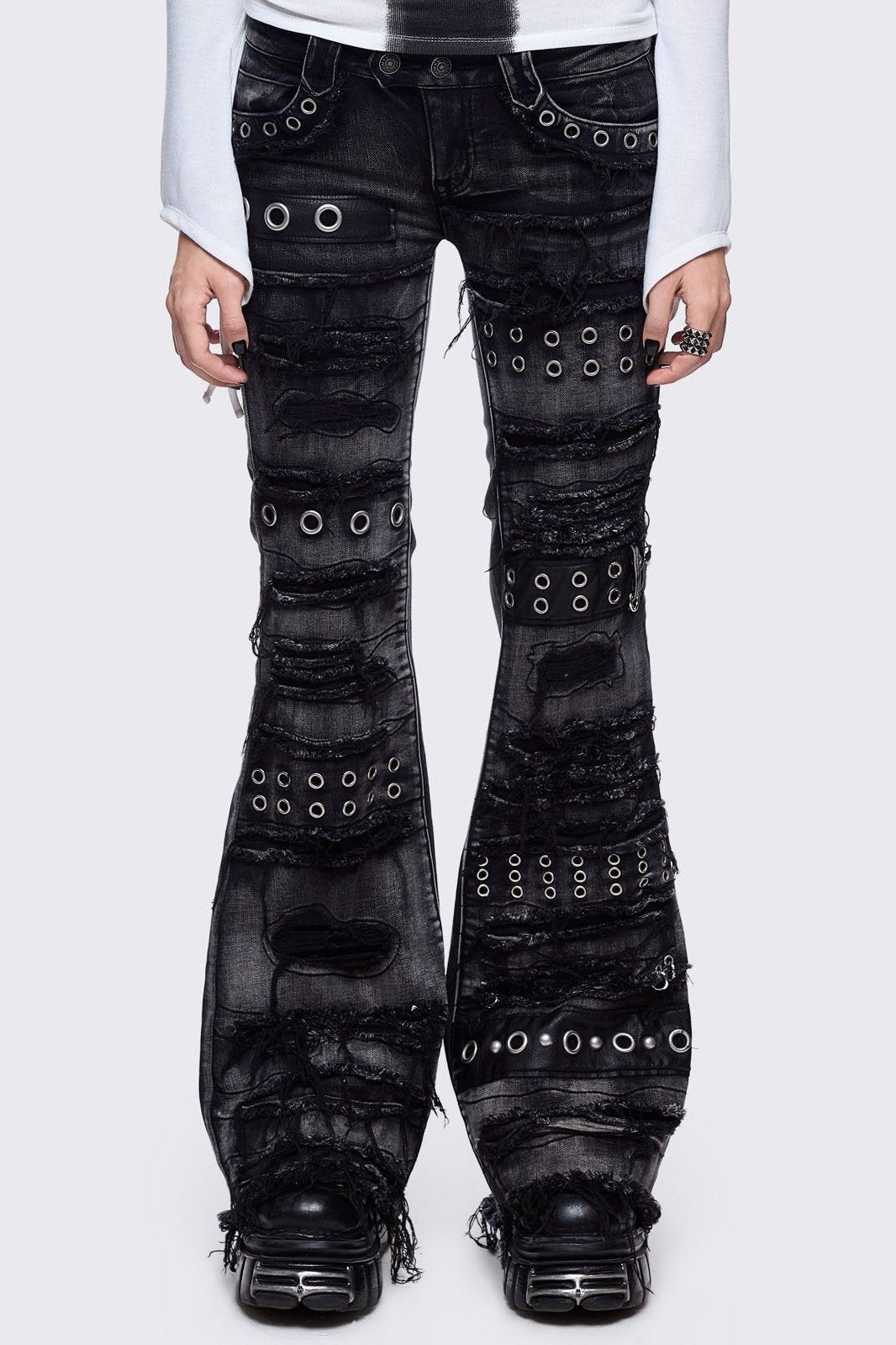 Black washed flare jeans featuring heavy distressed and shedded, eyelet, piercing and stud details. 