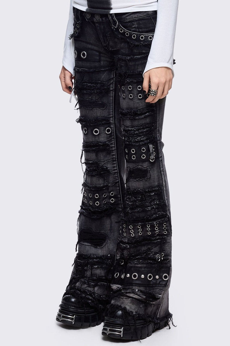 Black washed flare jeans featuring heavy distressed and shedded, eyelet, piercing and stud details. 
