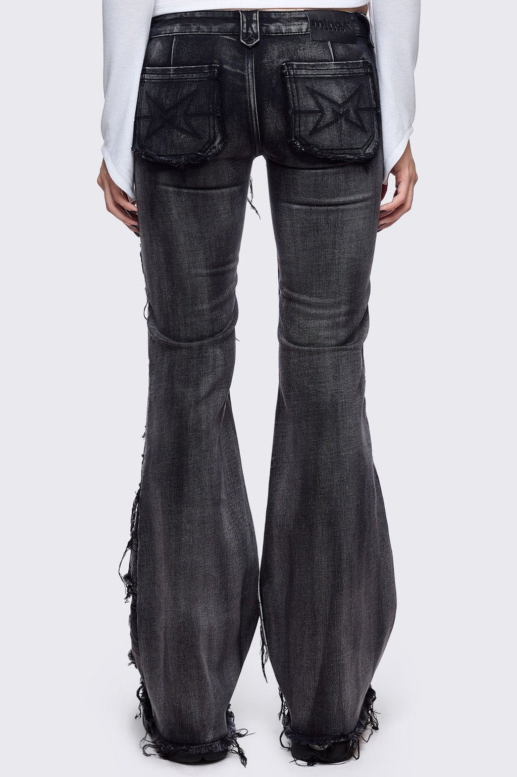 Black washed flare jeans featuring heavy distressed and shedded, eyelet, piercing and stud details. 