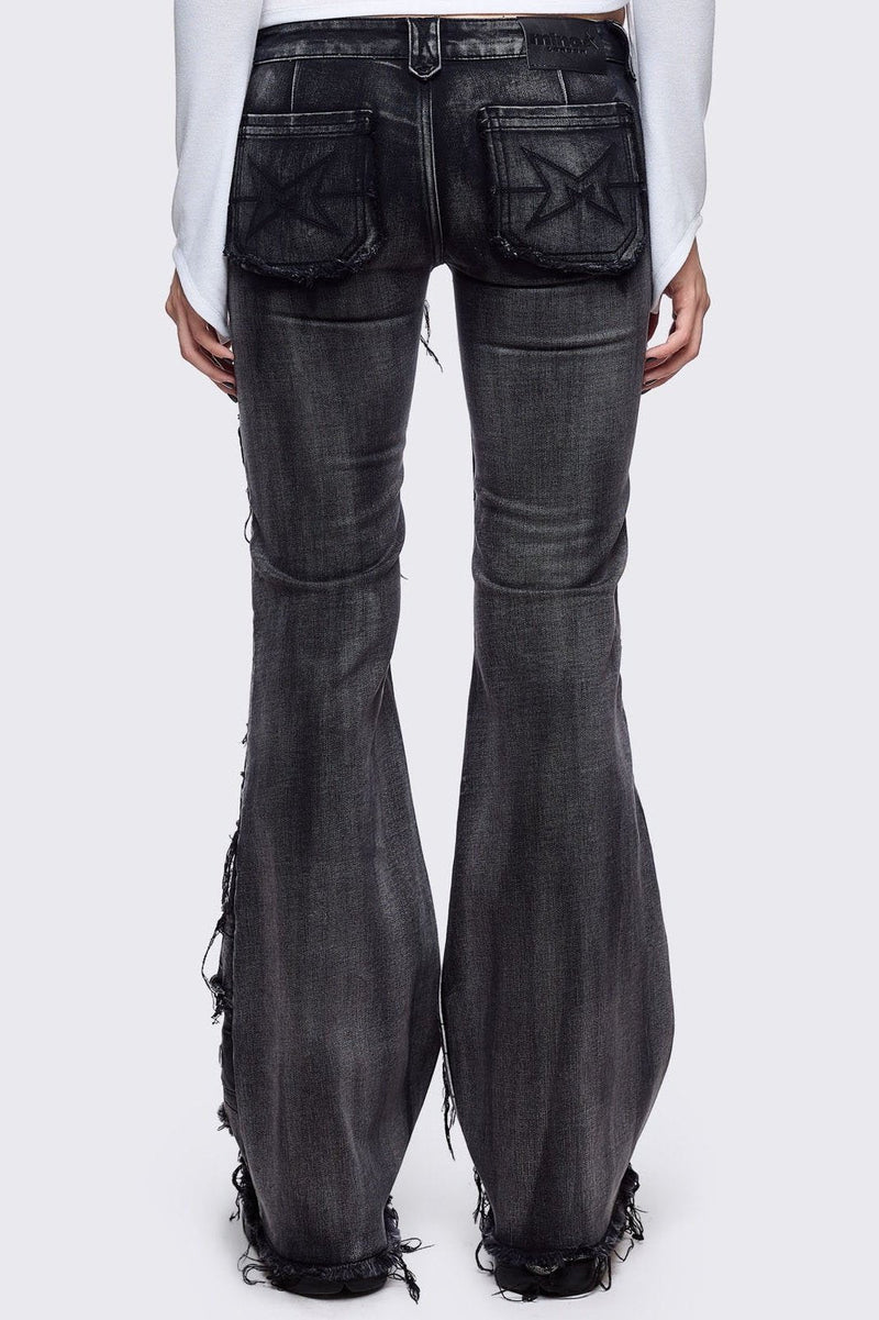 Black washed flare jeans featuring heavy distressed and shedded, eyelet, piercing and stud details. 