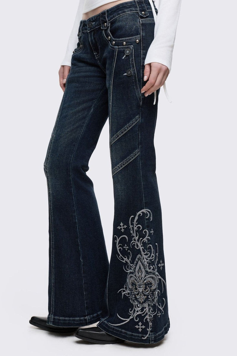 Dark blue wash flared jeans featuring gothic floral and fleur-de-lis embroidery on the lower legs and seams details. 