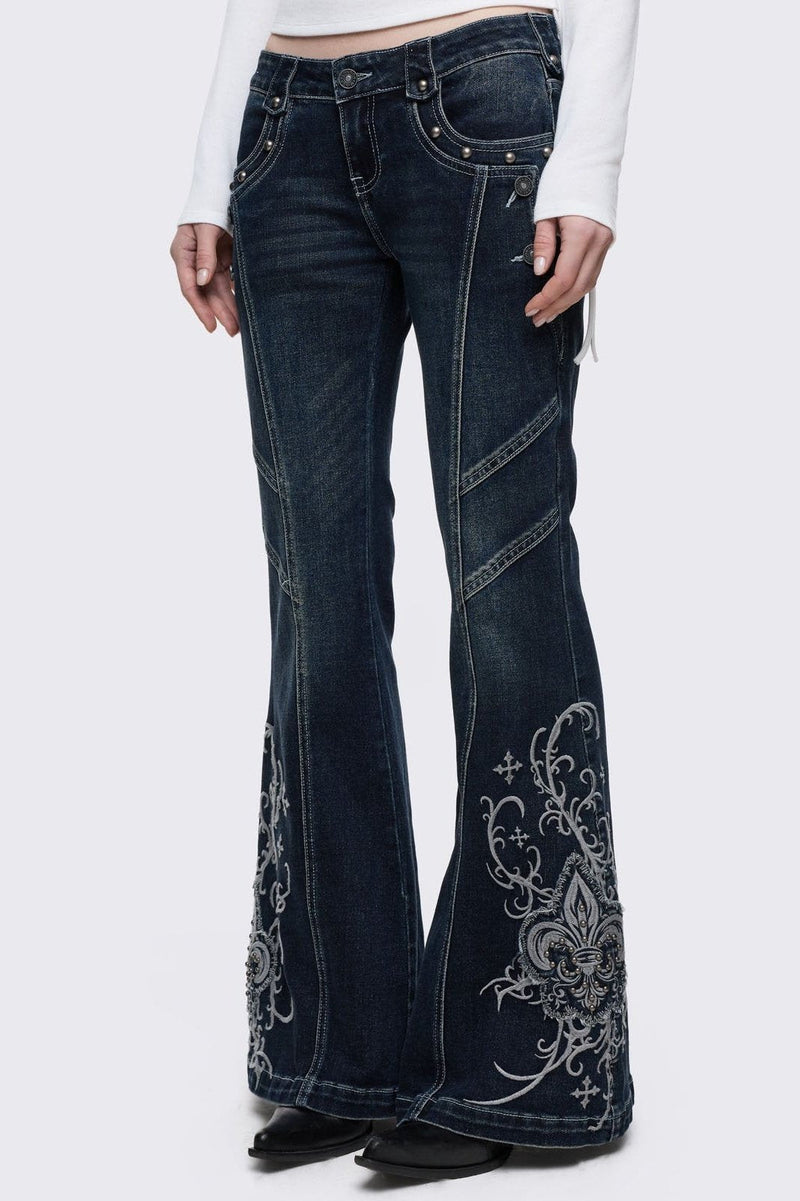 Dark blue wash flared jeans featuring gothic floral and fleur-de-lis embroidery on the lower legs and seams details. 