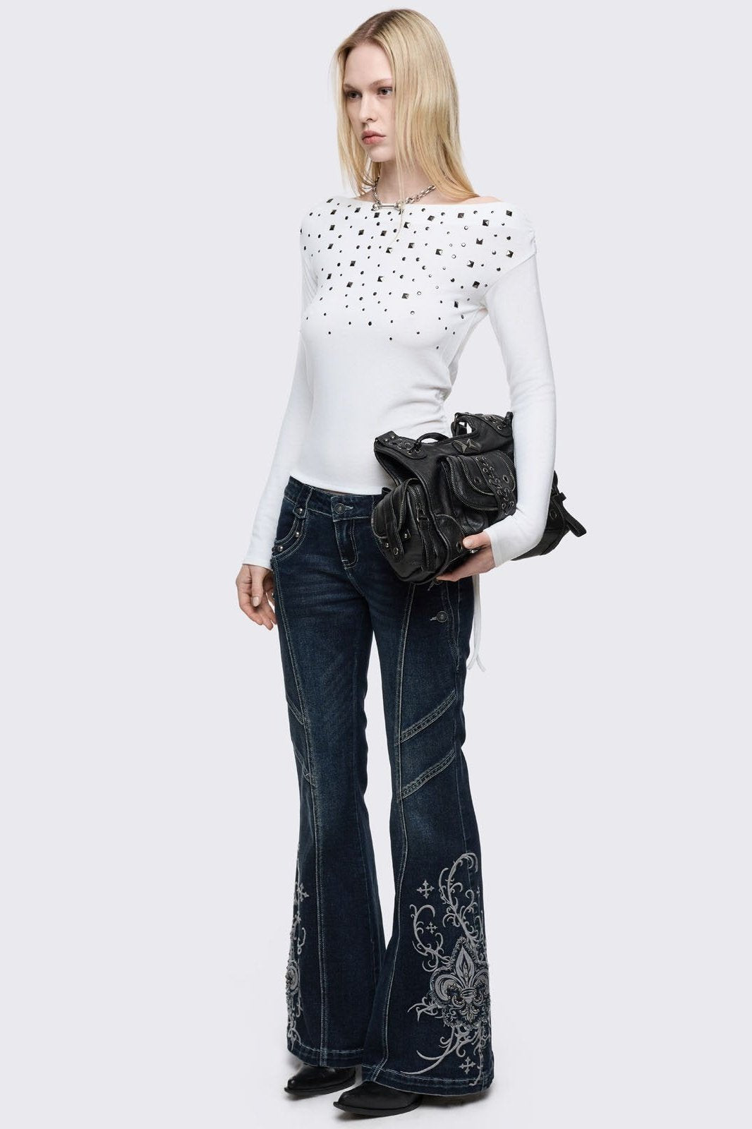 Dark blue wash flared jeans featuring gothic floral and fleur-de-lis embroidery on the lower legs and seams details. 