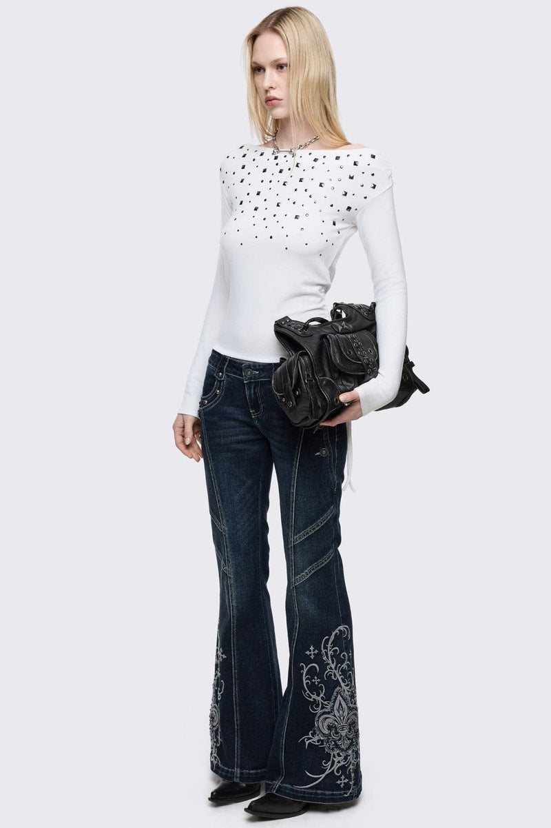 Dark blue wash flared jeans featuring gothic floral and fleur-de-lis embroidery on the lower legs and seams details. 