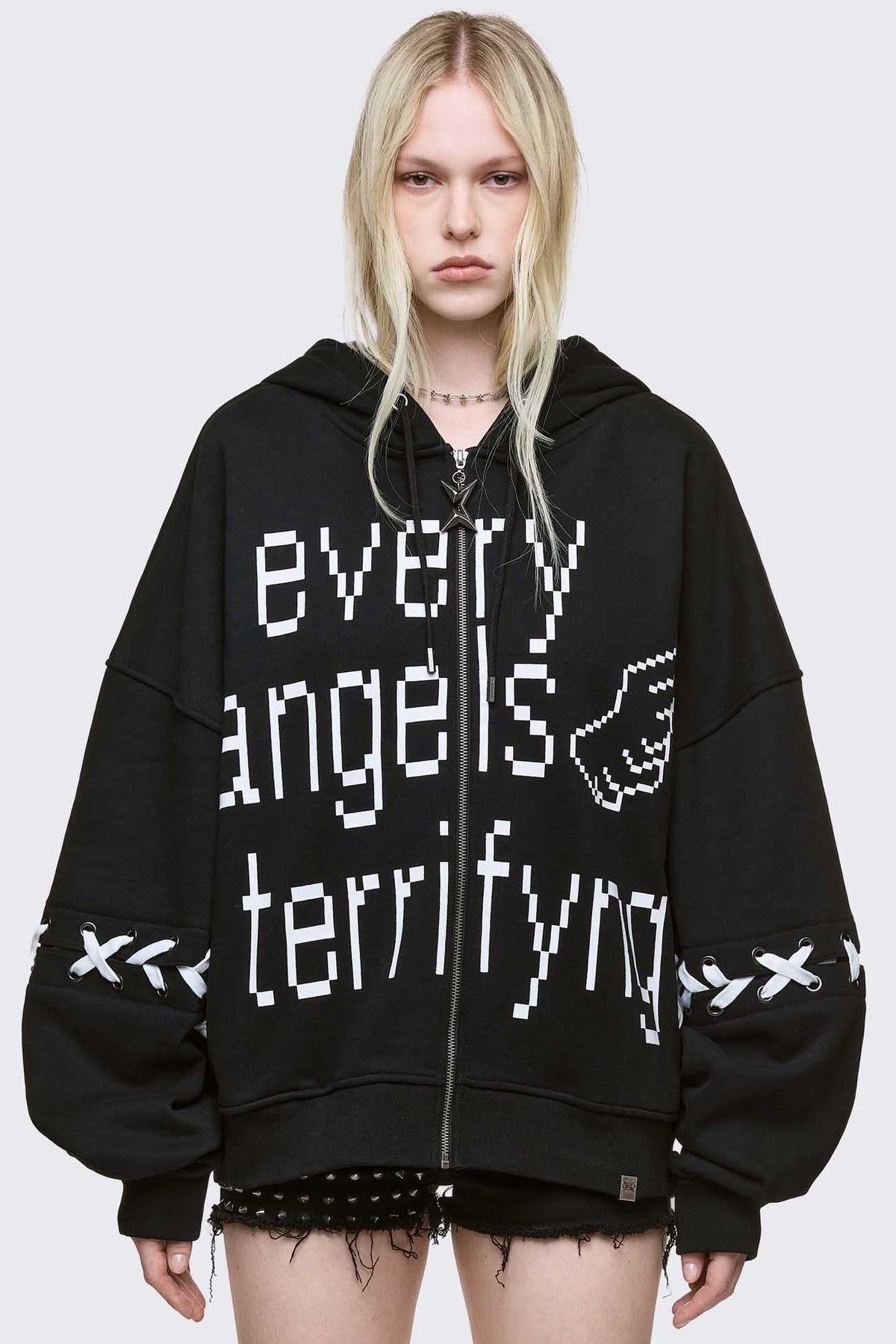 Black zip up hoodie jacket with "Every angels terrifying" graphic print and white lace-up details.