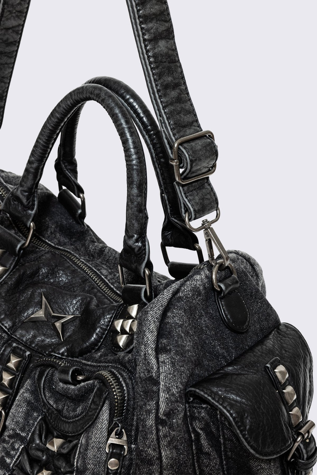 Black acid-wash denim shoulder bag with studs, ruched pockets and buckle details in a grunge Y2K style.