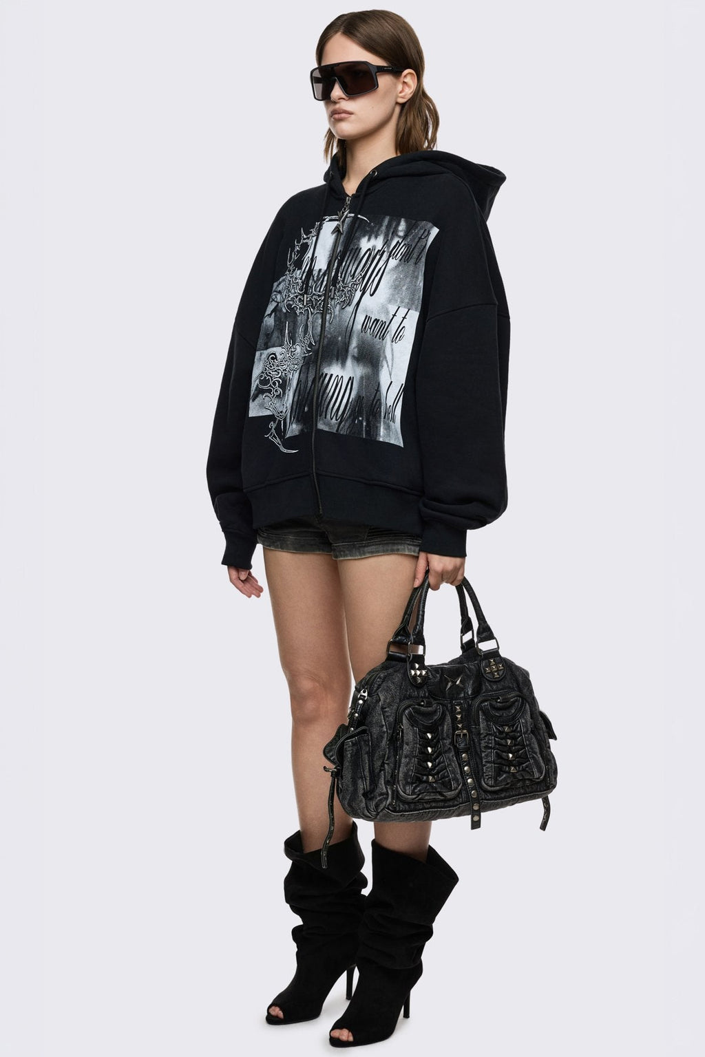 Black acid-wash denim shoulder bag with studs, ruched pockets and buckle details in a grunge Y2K style.