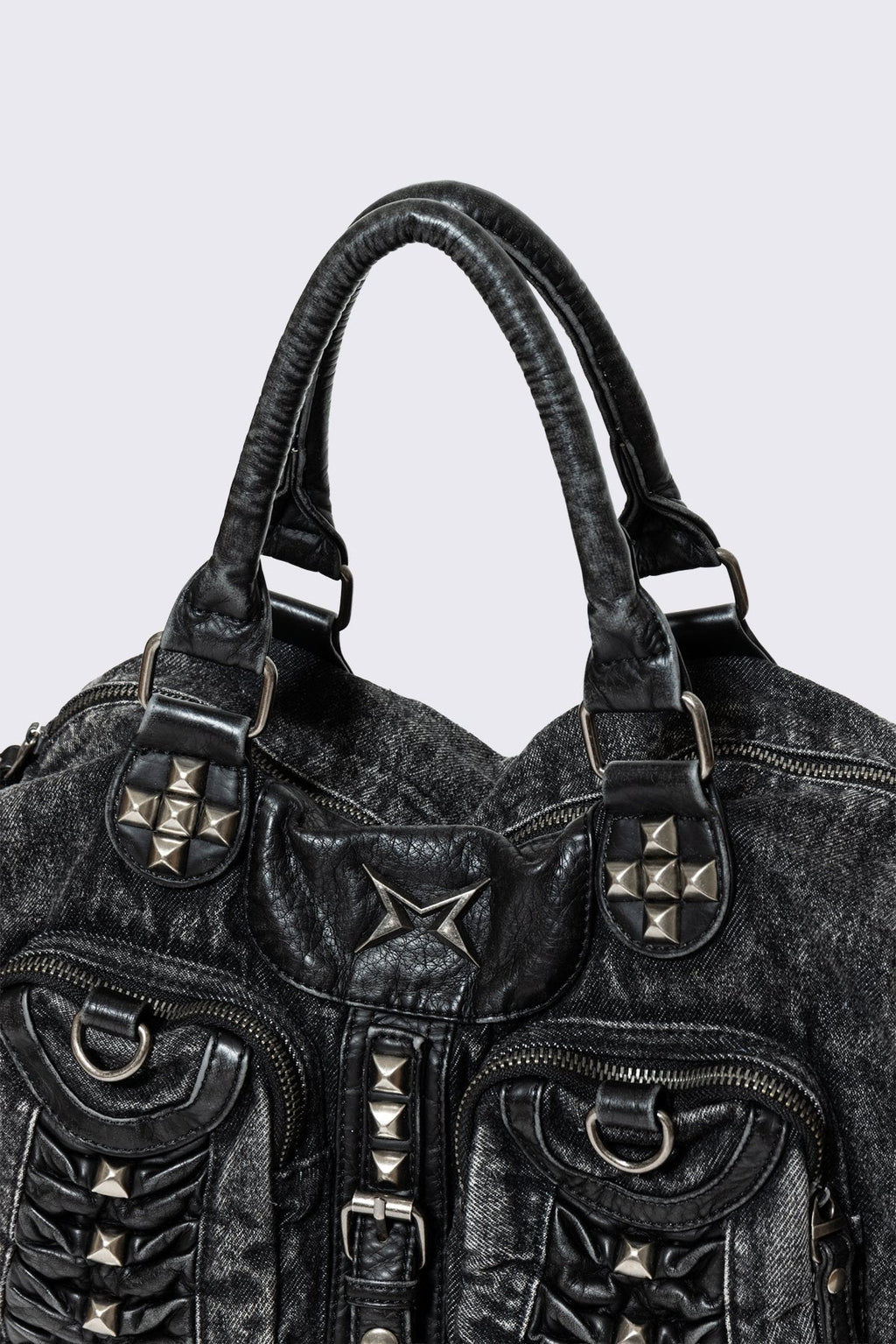 Black acid-wash denim shoulder bag with studs, ruched pockets and buckle details in a grunge Y2K style.