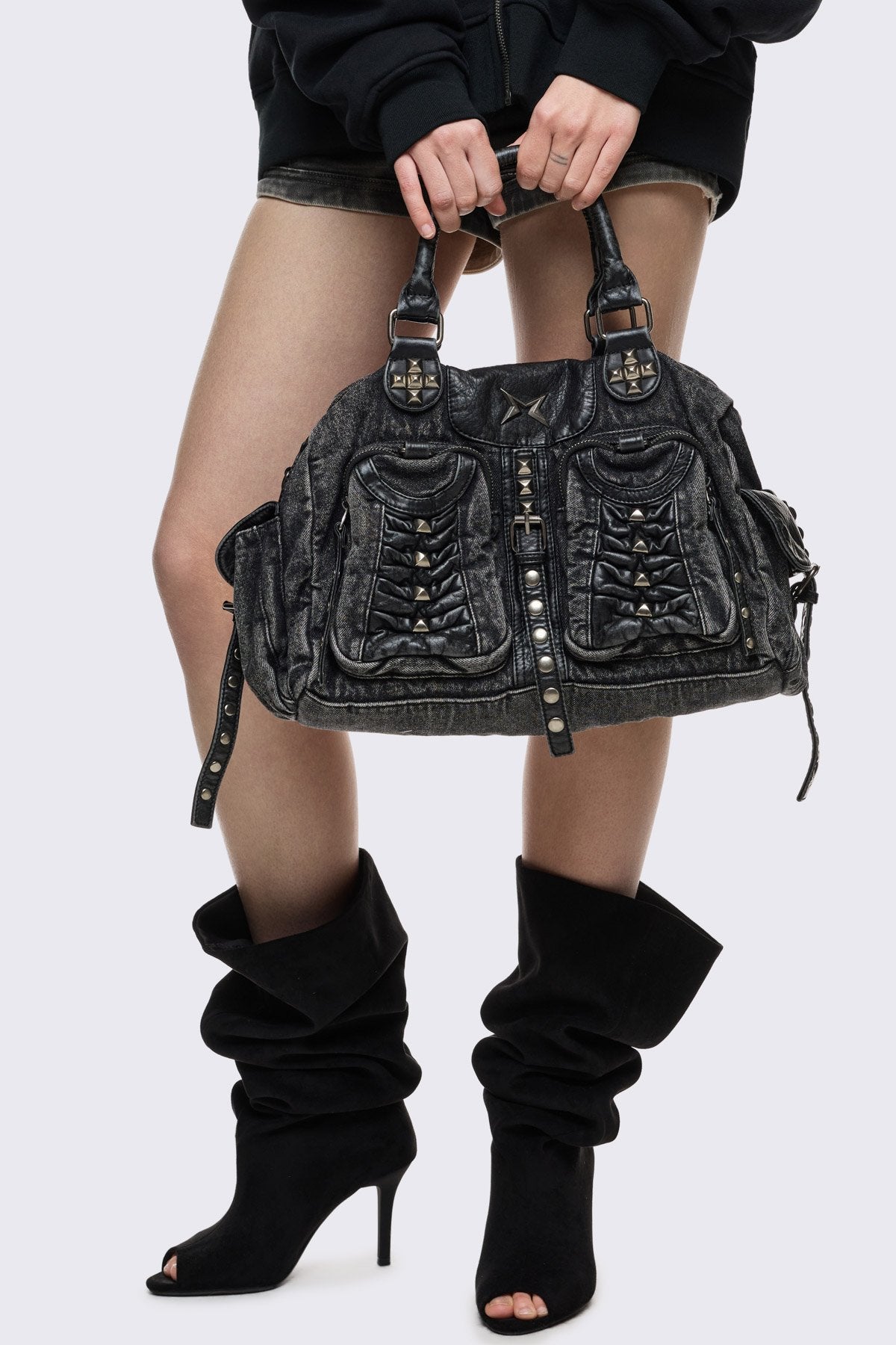 Black acid-wash denim shoulder bag with studs, ruched pockets and buckle details in a grunge Y2K style.