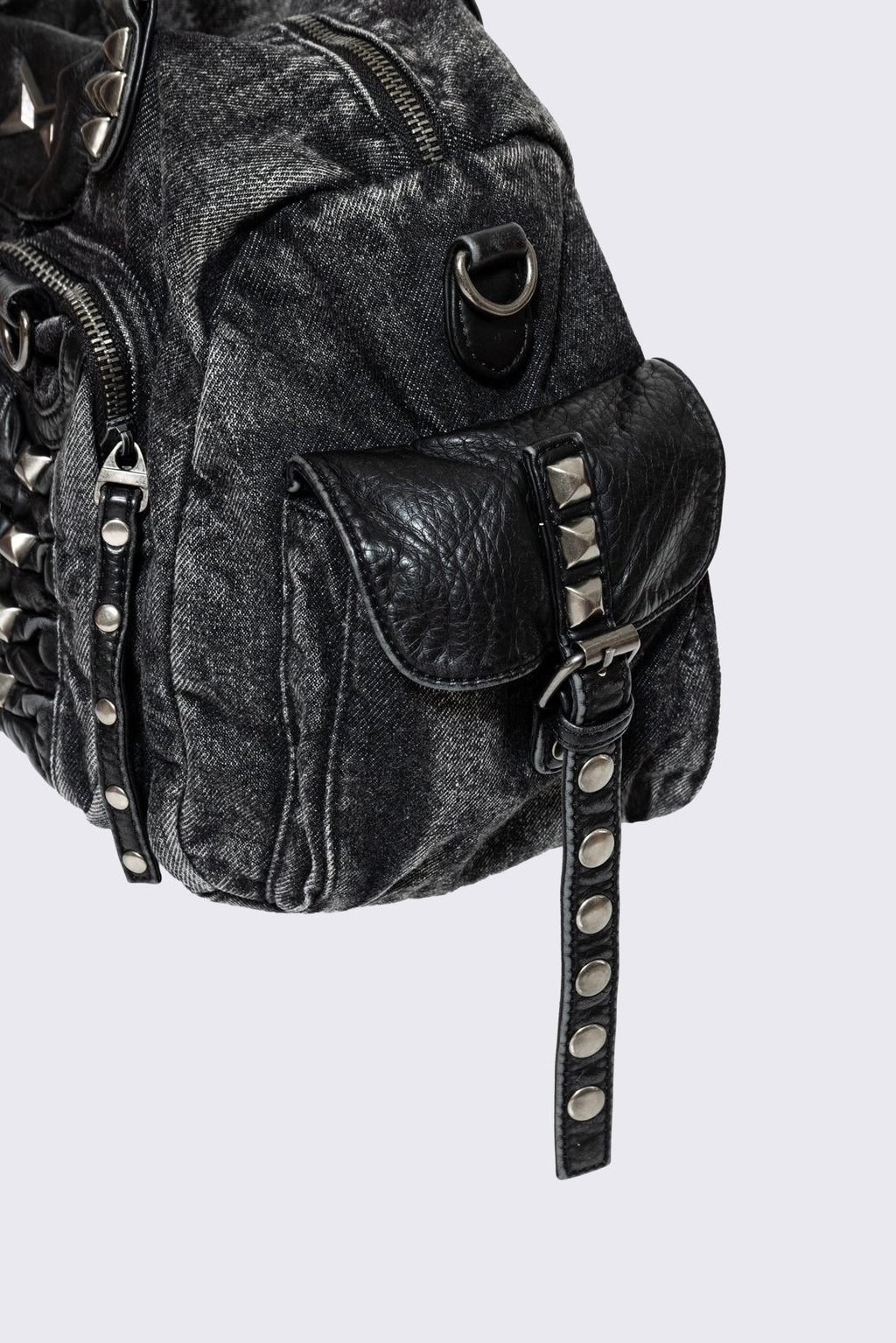 Black acid-wash denim shoulder bag with studs, ruched pockets and buckle details in a grunge Y2K style.